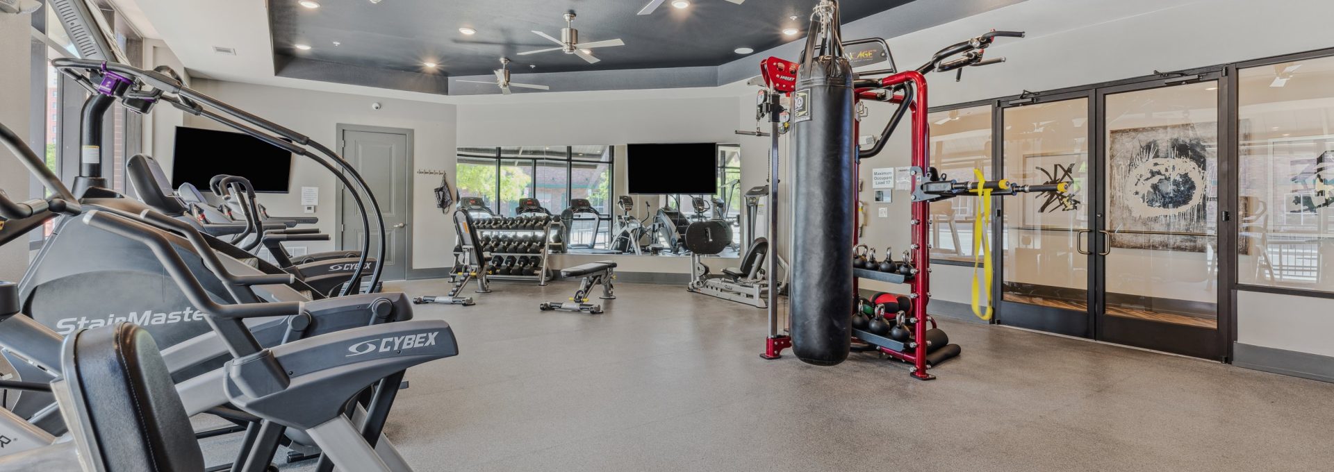 a gym room with exercise equipment and ceiling fans at The Steelyard Apartments